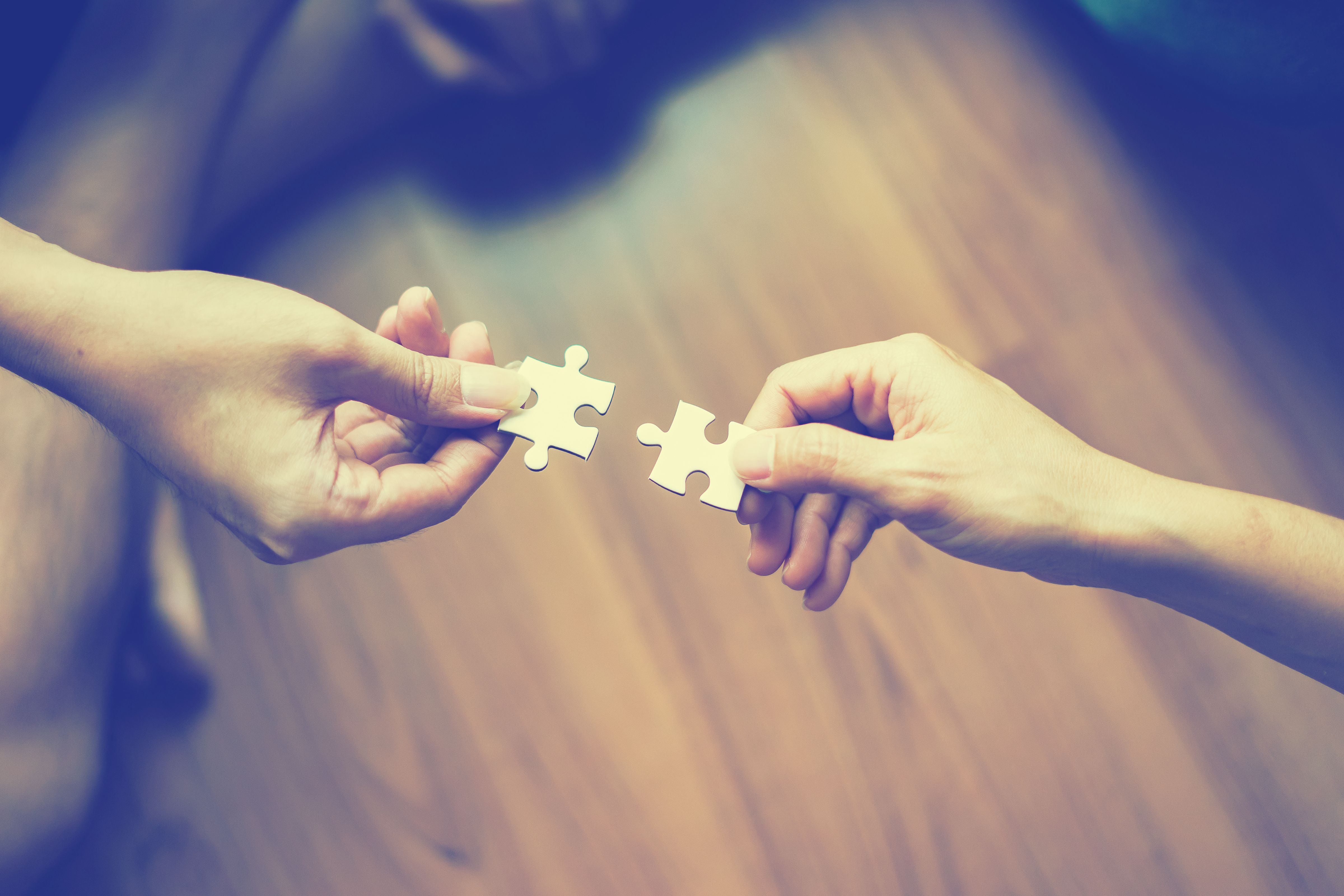 two hands trying to connect couple puzzle piece Jigsaw alone wooden puzzle Teamwork, partnership, business idea, cooperation management concept